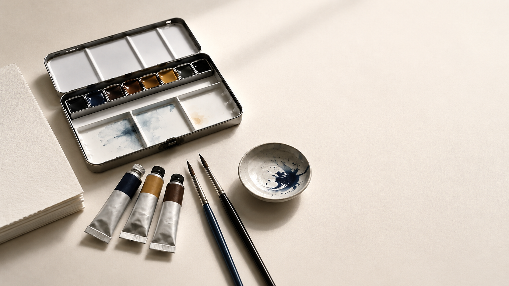 Watercolour starter materials including palette, paint tubes, brushes and paper